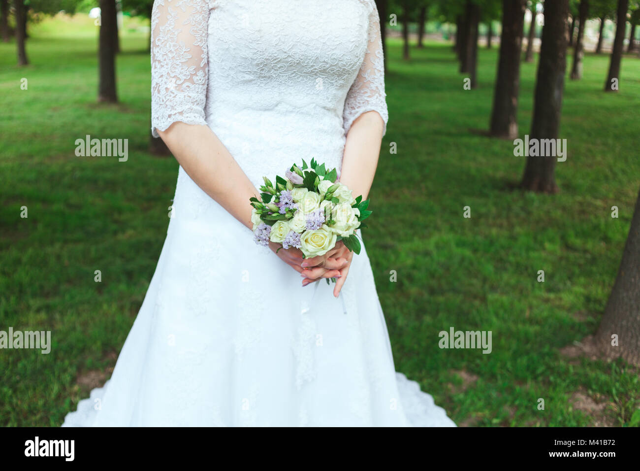 Beautiful bride in white wedding dress holding bouquet Stock Photo - Alamy