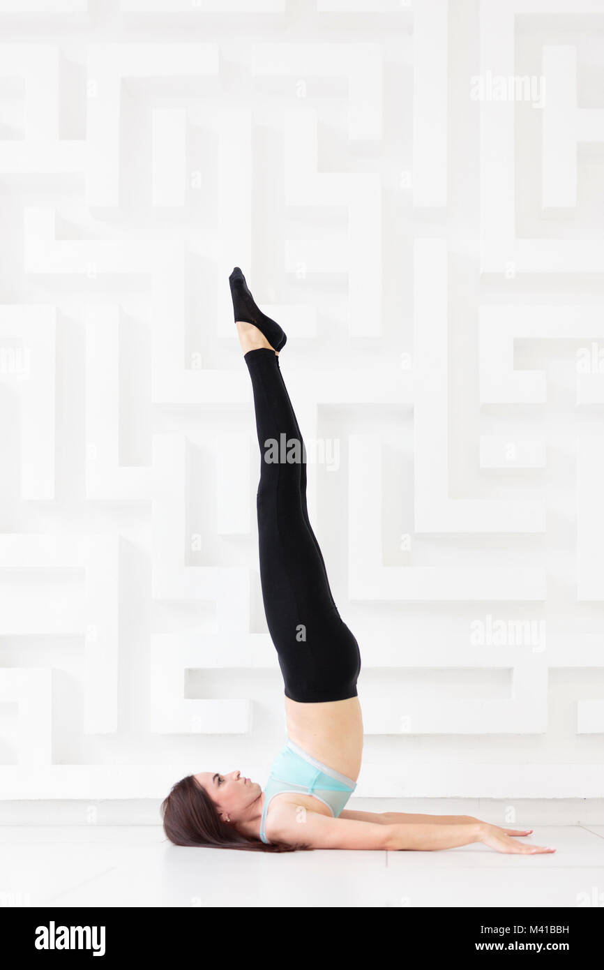 Young woman practicing yoga over white wall Stock Photo - Alamy