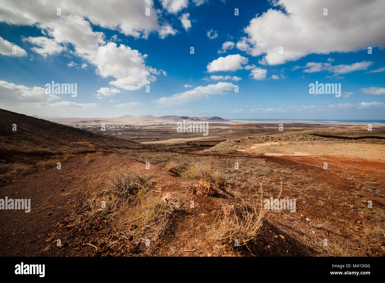 Amazing vulcanic landscape with mountains. Sky is blue with clouds, gravel is red and brown. Fuerteventura Island, Canary Island, Spain, Europe. Stock Photo