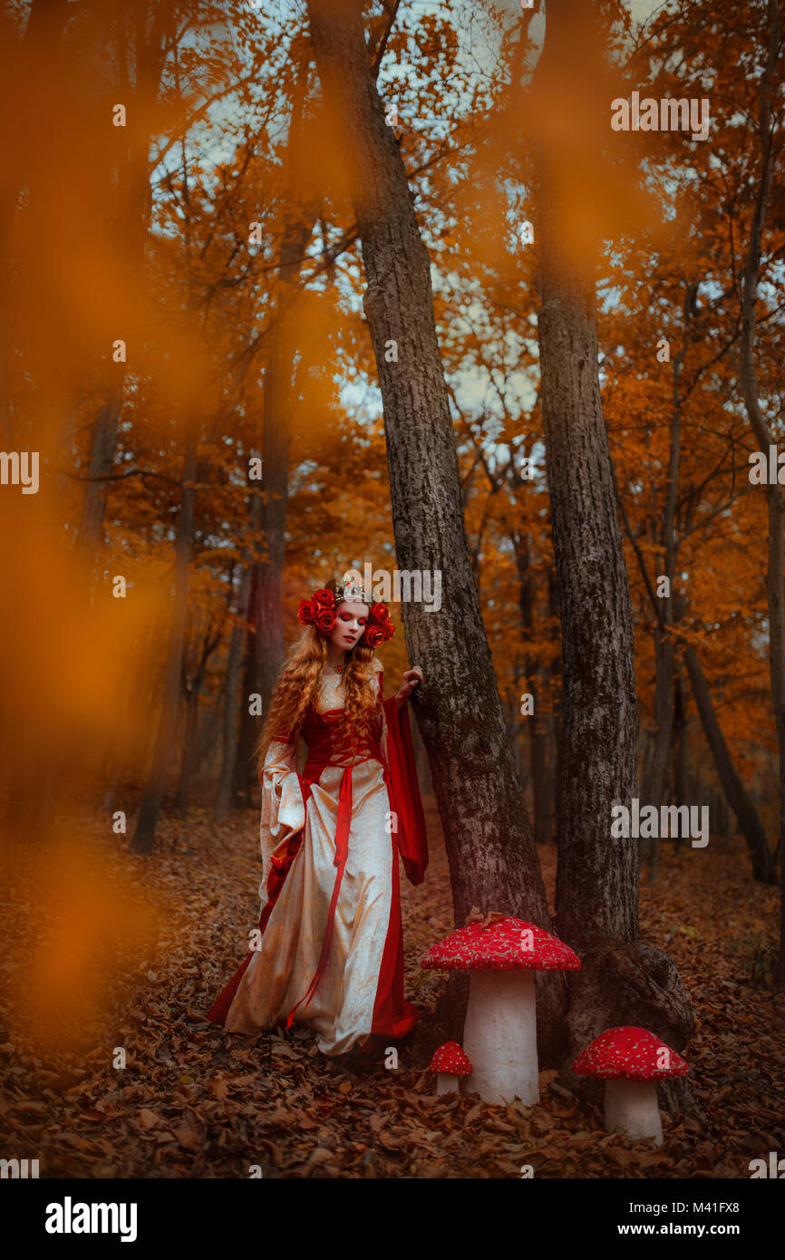 A young woman in red medieval dress walking in wonderland Stock Photo