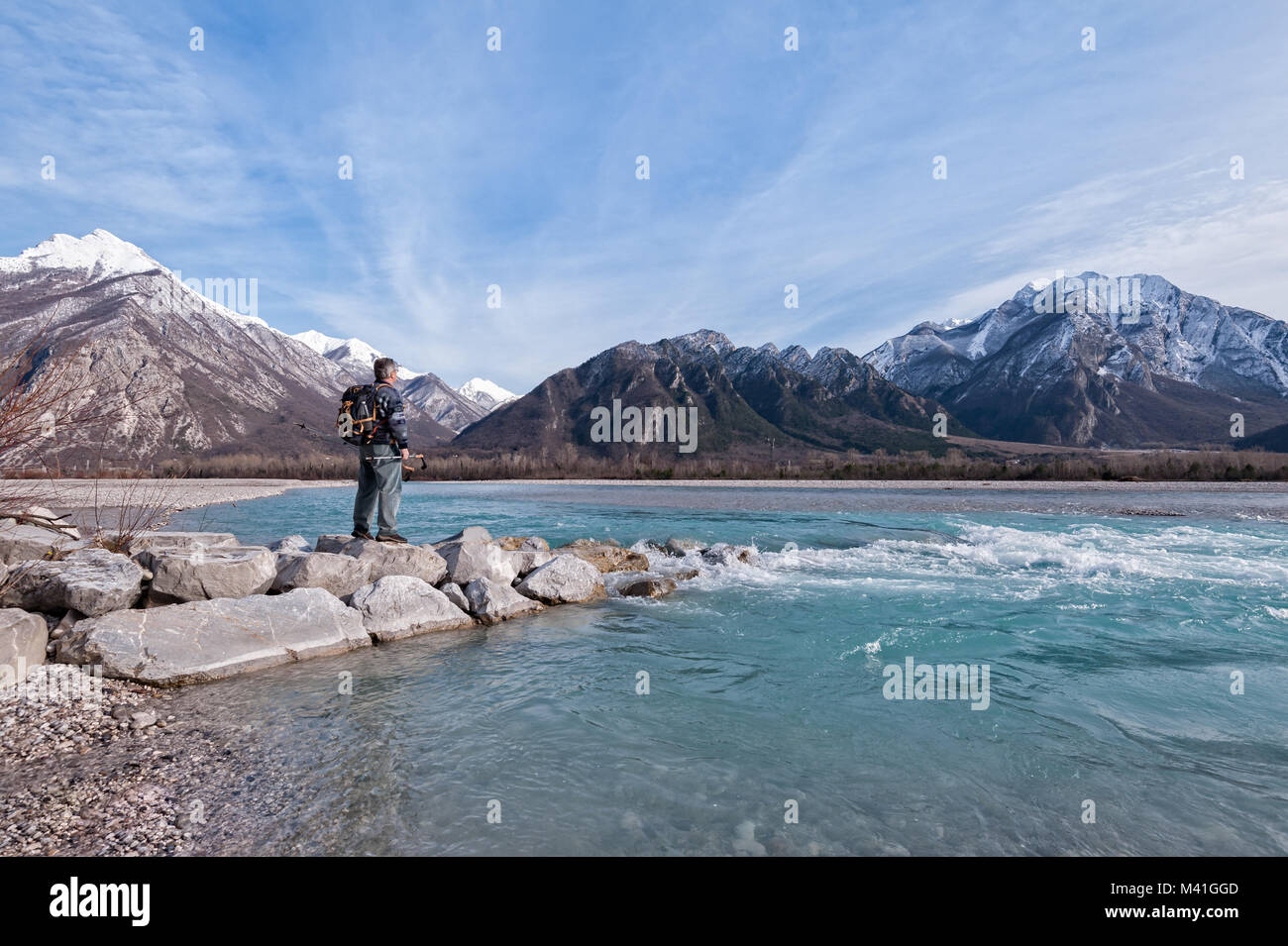Man hiker enjoys view of the river and mountains. Alps Italy Friuli Venezia Giulia. Stock Photo