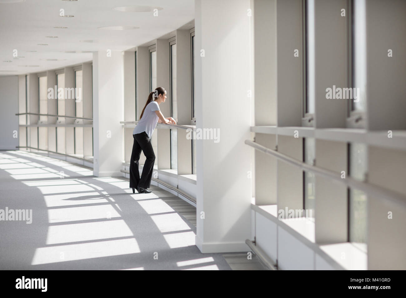 Businesswoman looking out of window in office Stock Photo