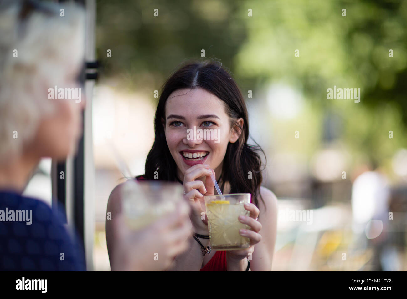 Female friends enjoying a refreshing drink outdoors in summer Stock Photo