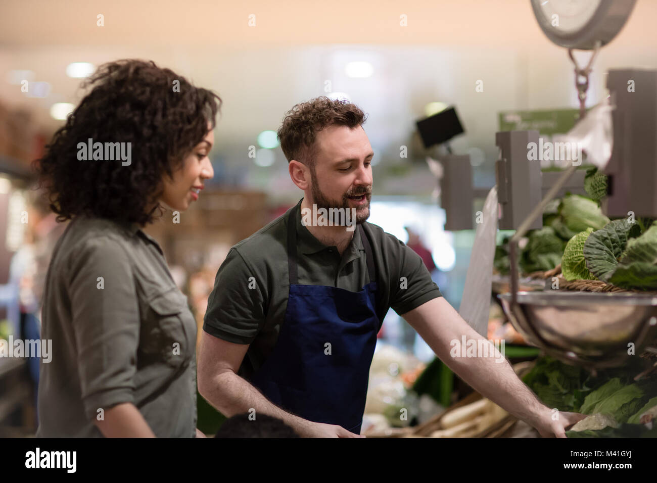 Shop assistant in grocery store helping shopper Stock Photo
