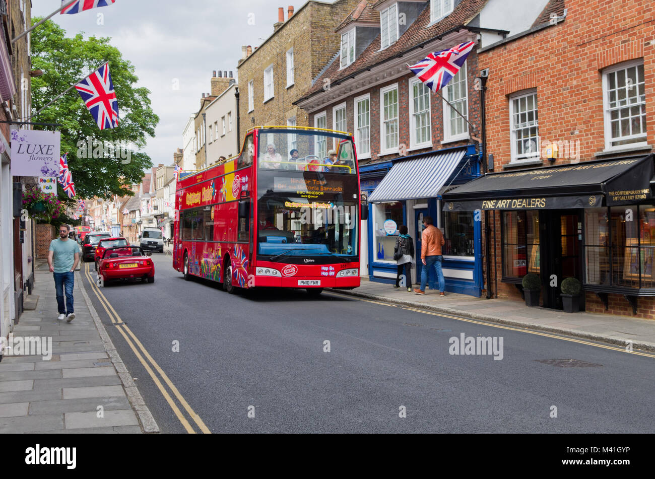 An open top tourist bus driving down Eton High Street on a sunny Summer's day; Windsor and Eton, UK Stock Photo
