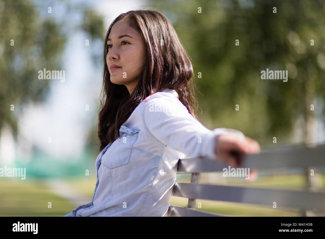 Woman sitting on bench in with takeout coffee Stock Photo