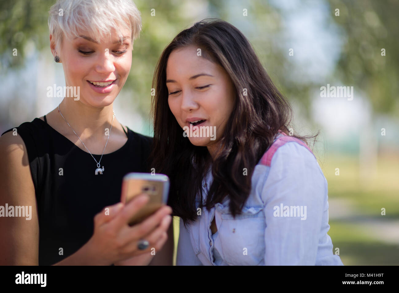 Female friends looking at smartphone Stock Photo