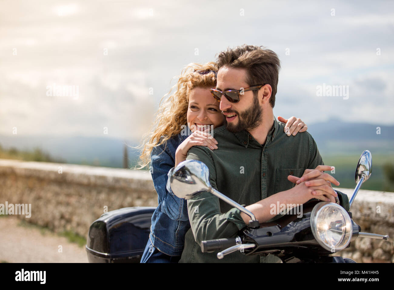 Young couple on motorbike together looking at view Stock Photo