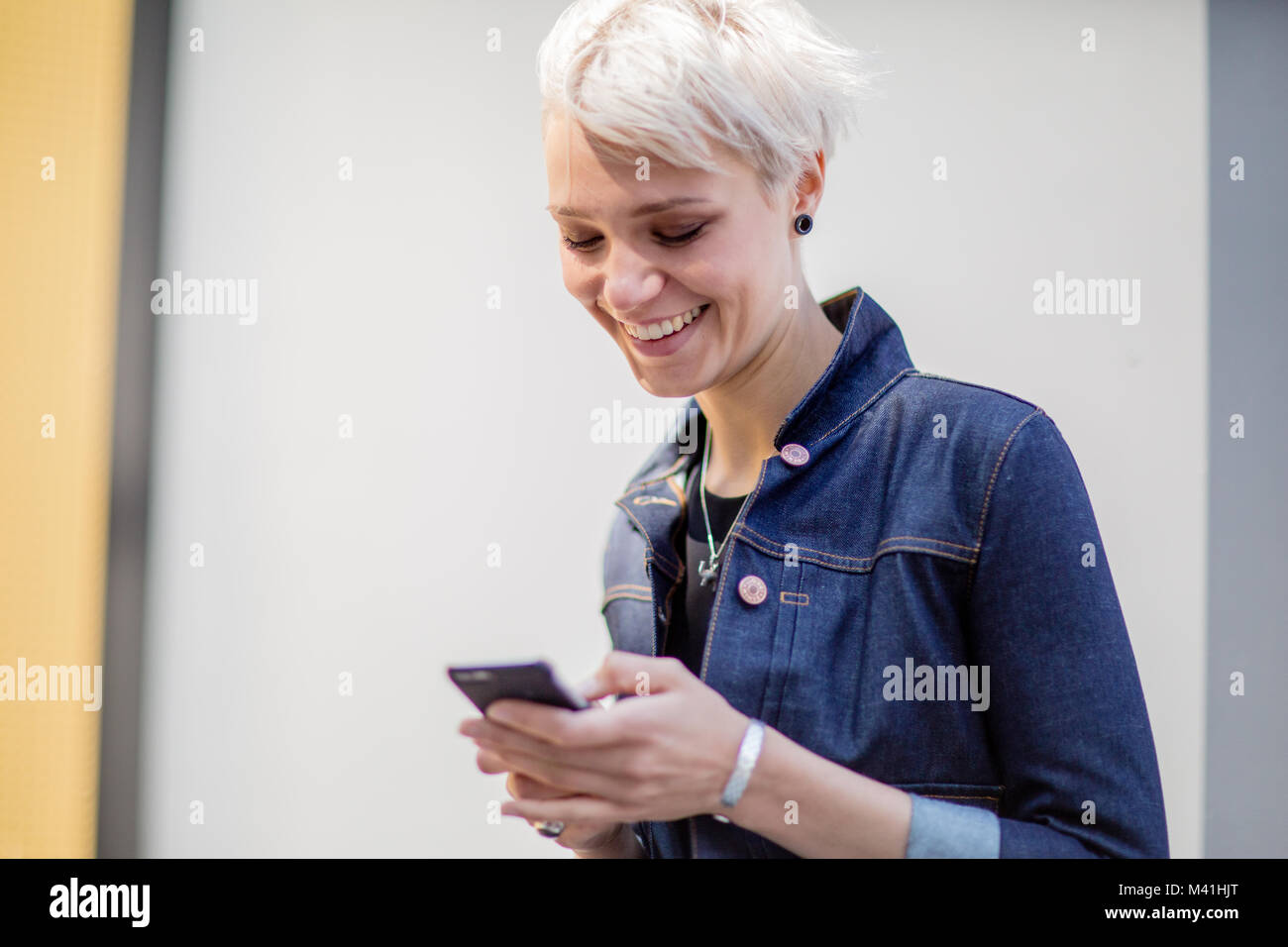Young adult walking down street and checking smartphone Stock Photo