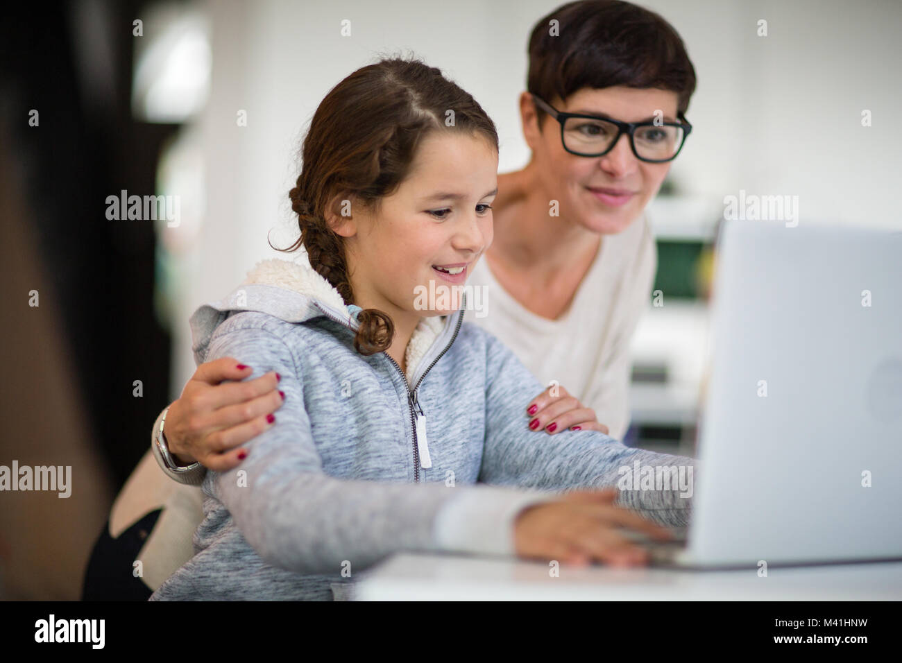 Daughter showing mum her homework on laptop Stock Photo