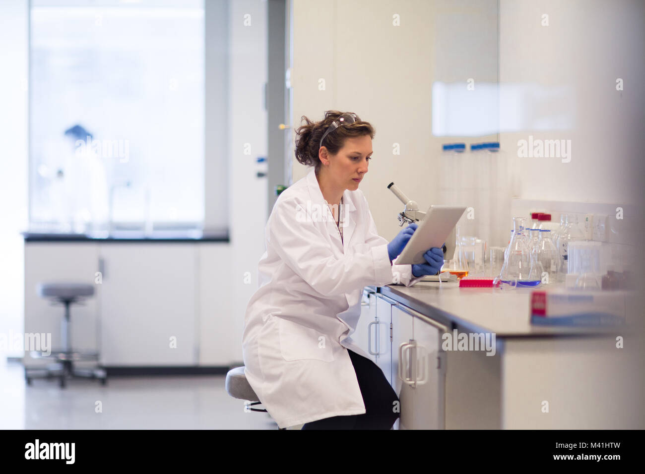 Female scientist looking at results of experiment on digital tablet Stock Photo