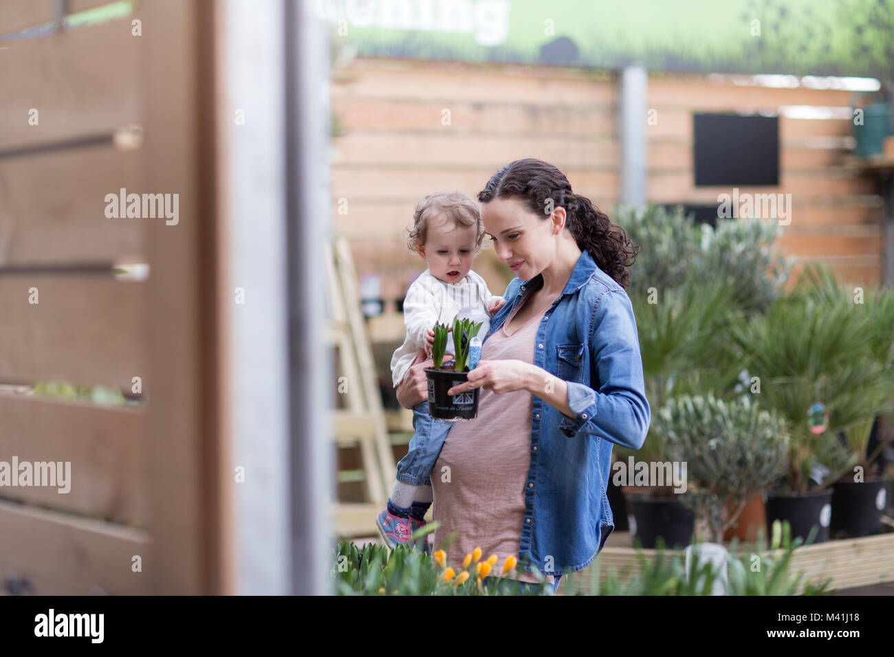 Pregnant mother with daughter at garden centre Stock Photo