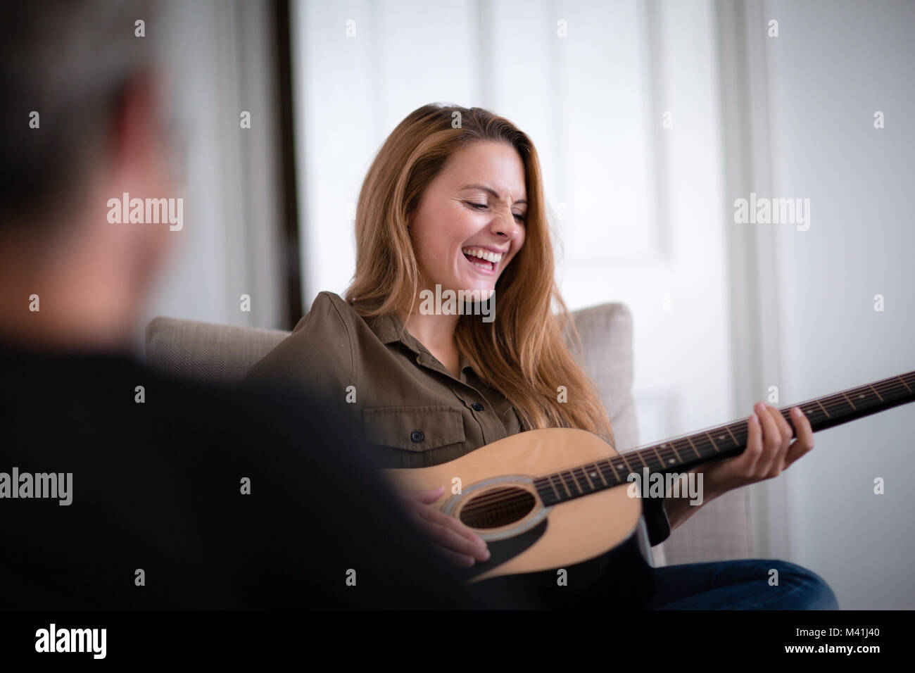 Young adult female playing acoustic guitar to friend Stock Photo