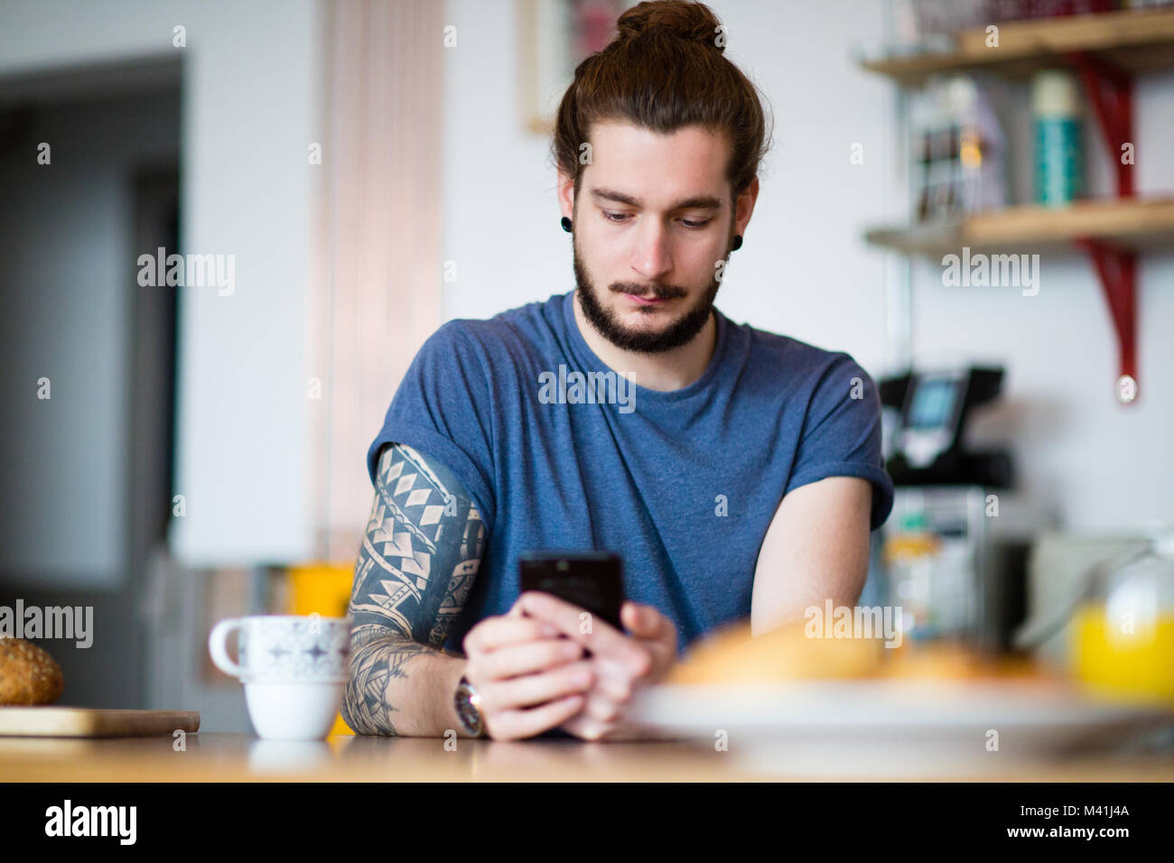 Young adult male having morning coffee and checking smartphone Stock Photo