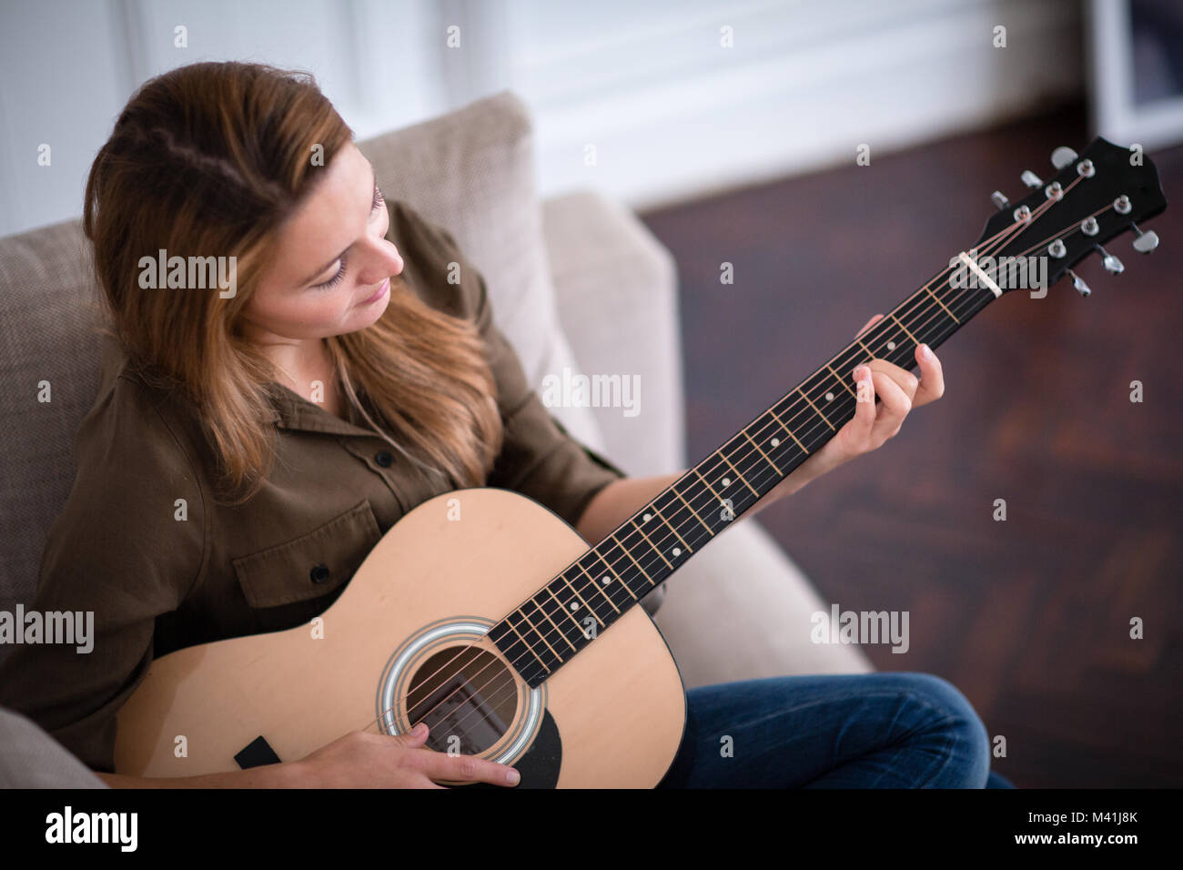 Young adult female playing acoustic guitar Stock Photo