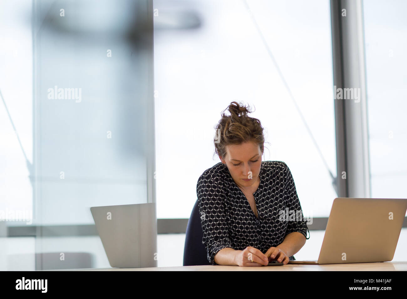 Female executive syncing smartphone to laptop Stock Photo