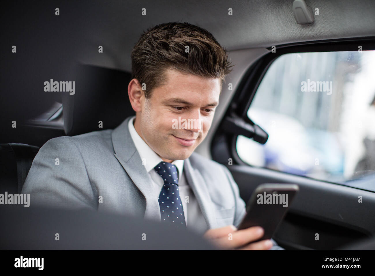Businessman in taxi cab using smartphone Stock Photo