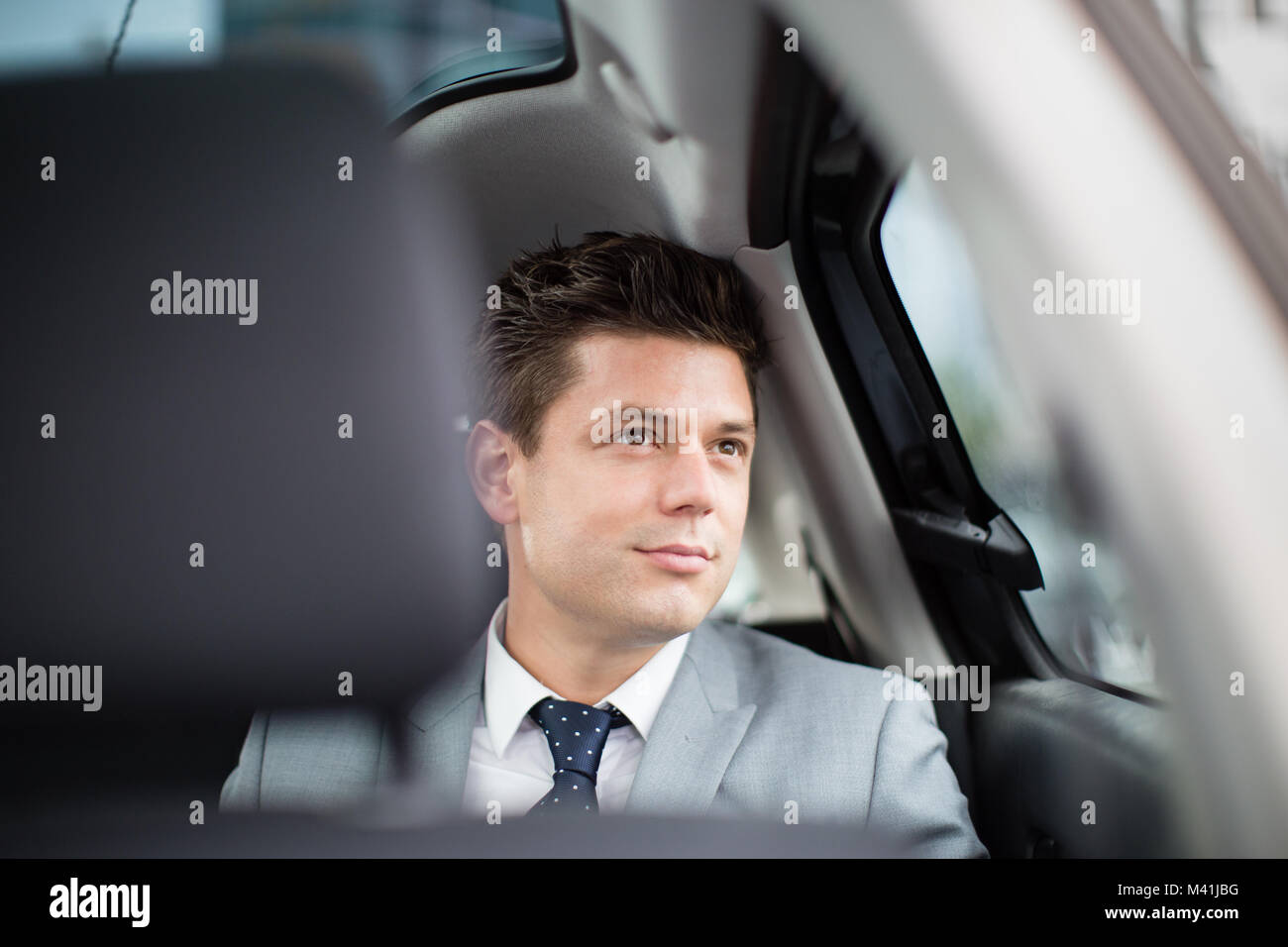 Businessman looking out of window of taxi cab Stock Photo