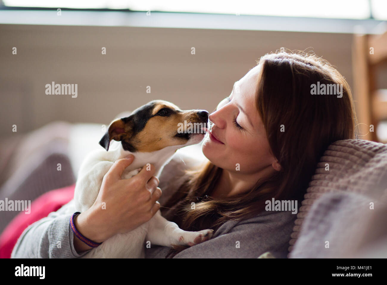 Young female with puppy at home Stock Photo