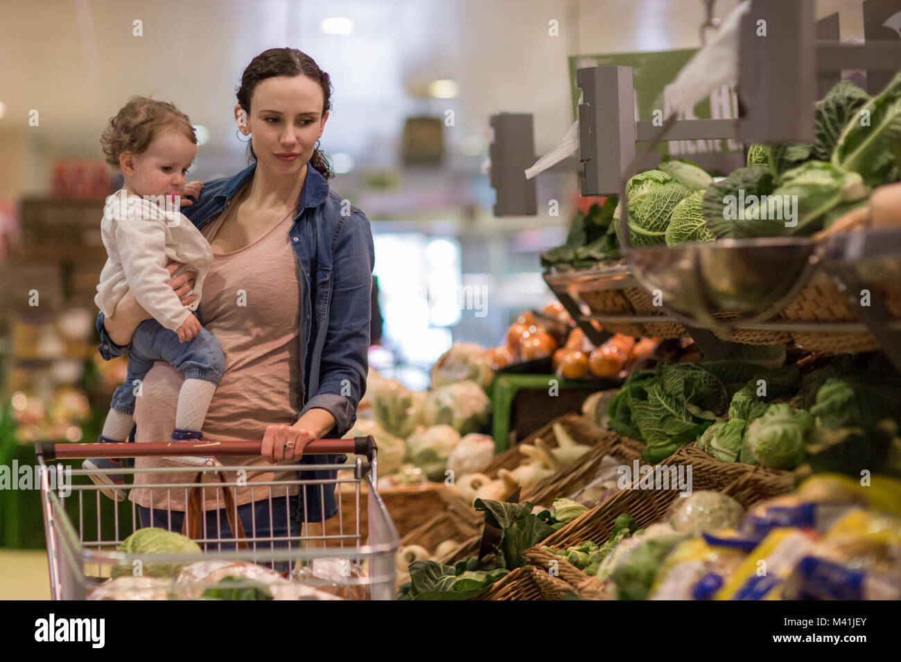 Mother and daughter buying vegetables in grocery store Stock Photo