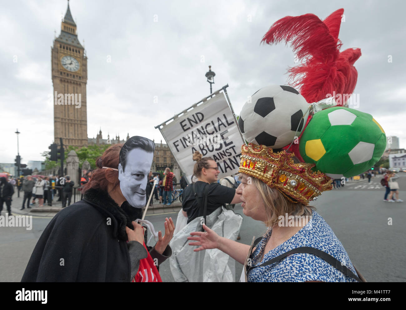 Protesters with Cameron mask and 'Balls to the Budget' headdress in front of the Houses of Parliament in DPAC budget day protest in Parliament Square Stock Photo