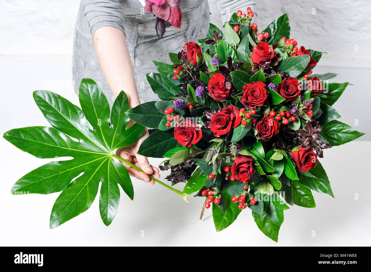 Woman showing how to arrange flowers from cutting to tying them together. Stock Photo