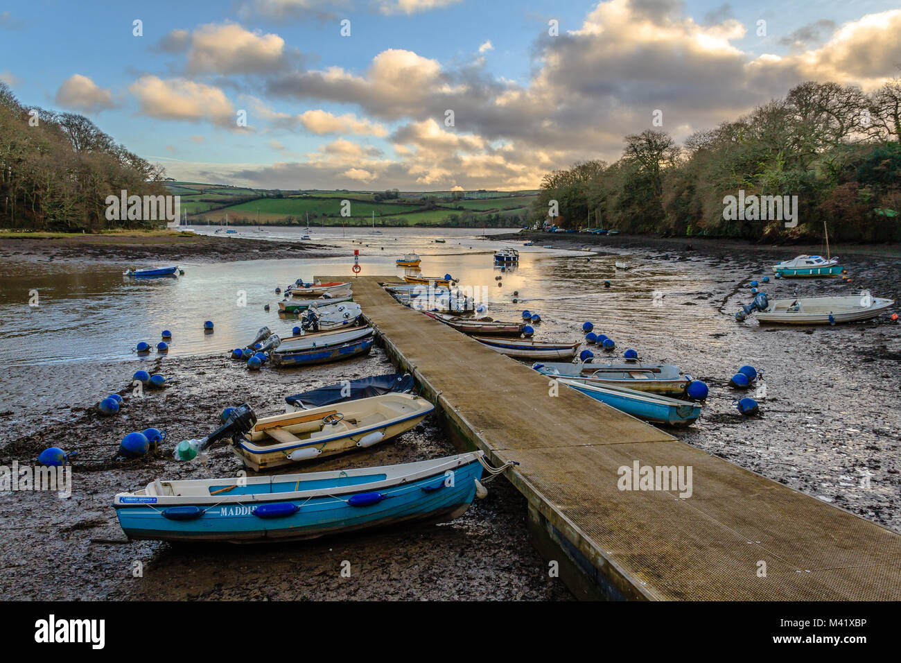 Boats moored up at low tide on a jetty on the Dart estuary at Stoke Gabriel in the evening. Devon, UK. January 2018. Stock Photo