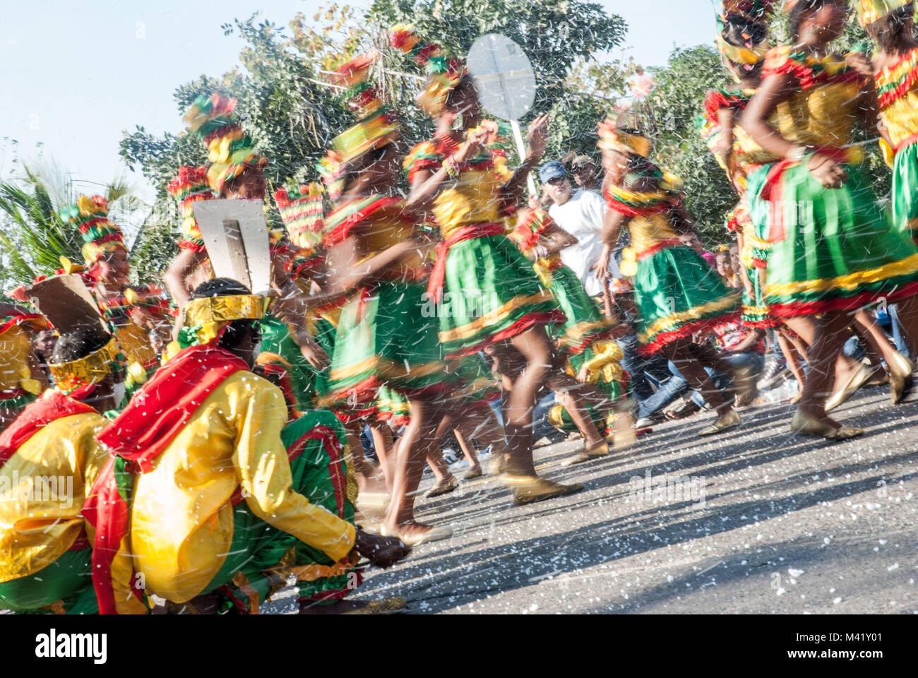 Children wearing colorful costumes dancing and celebrating with confetti during Barranquilla Carnival Stock Photo