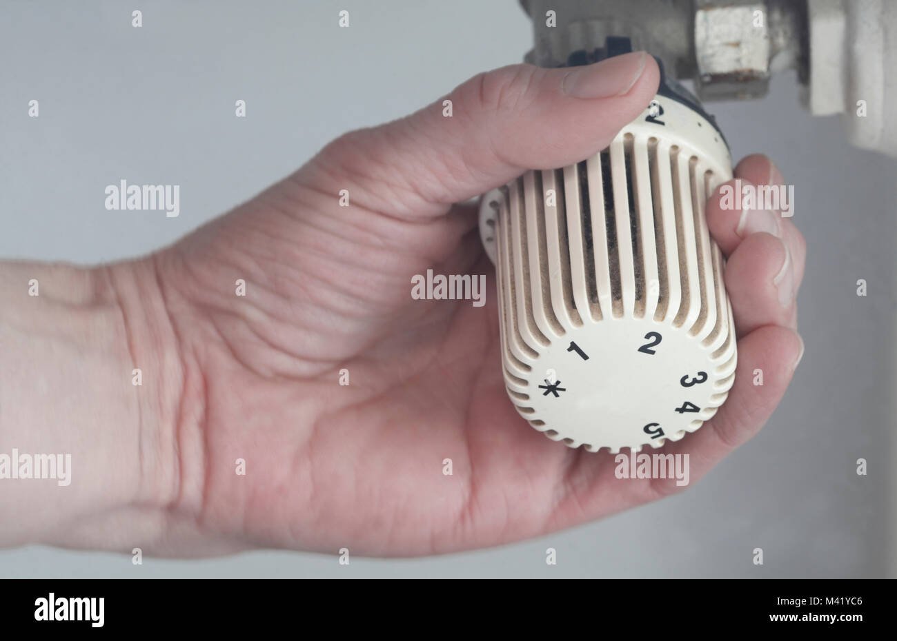 Hand puts the temperature in a white heating thermostat Stock Photo Alamy