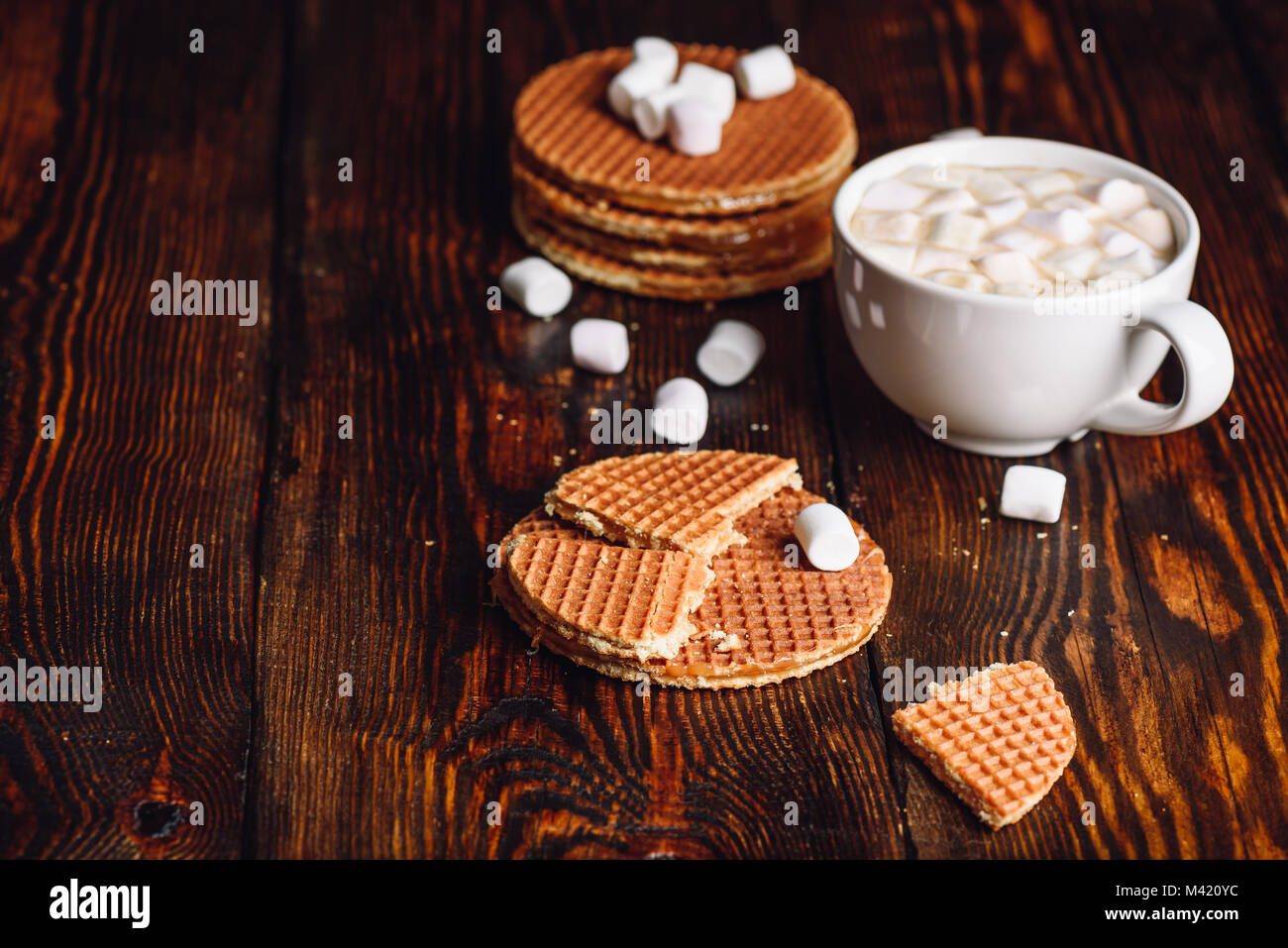Stroop Waffles with Broken One with White Cup of Hot Chocolate with Marshmallow and Waffle Stack. Copy Space on the Left. Stock Photo