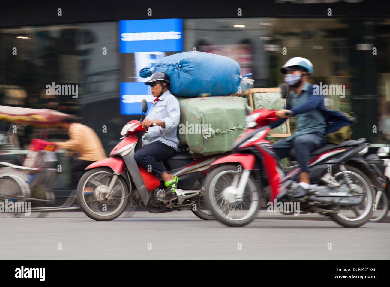man on speeding scooter with cargo in Hanoi, Vietnam Stock Photo