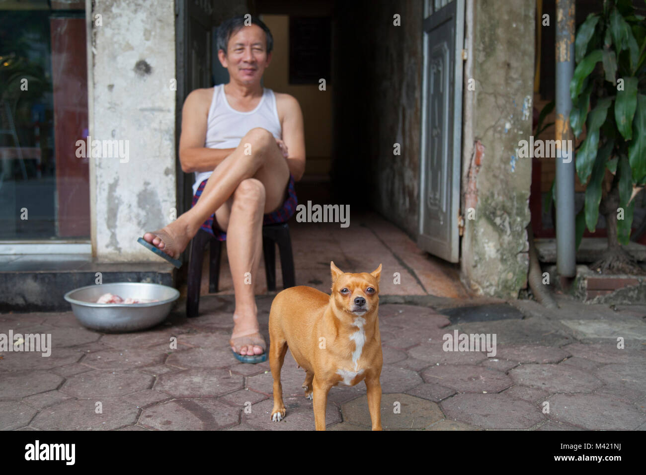 local vietnamese man and his dog outside their home in Hanoi, Vietnam
