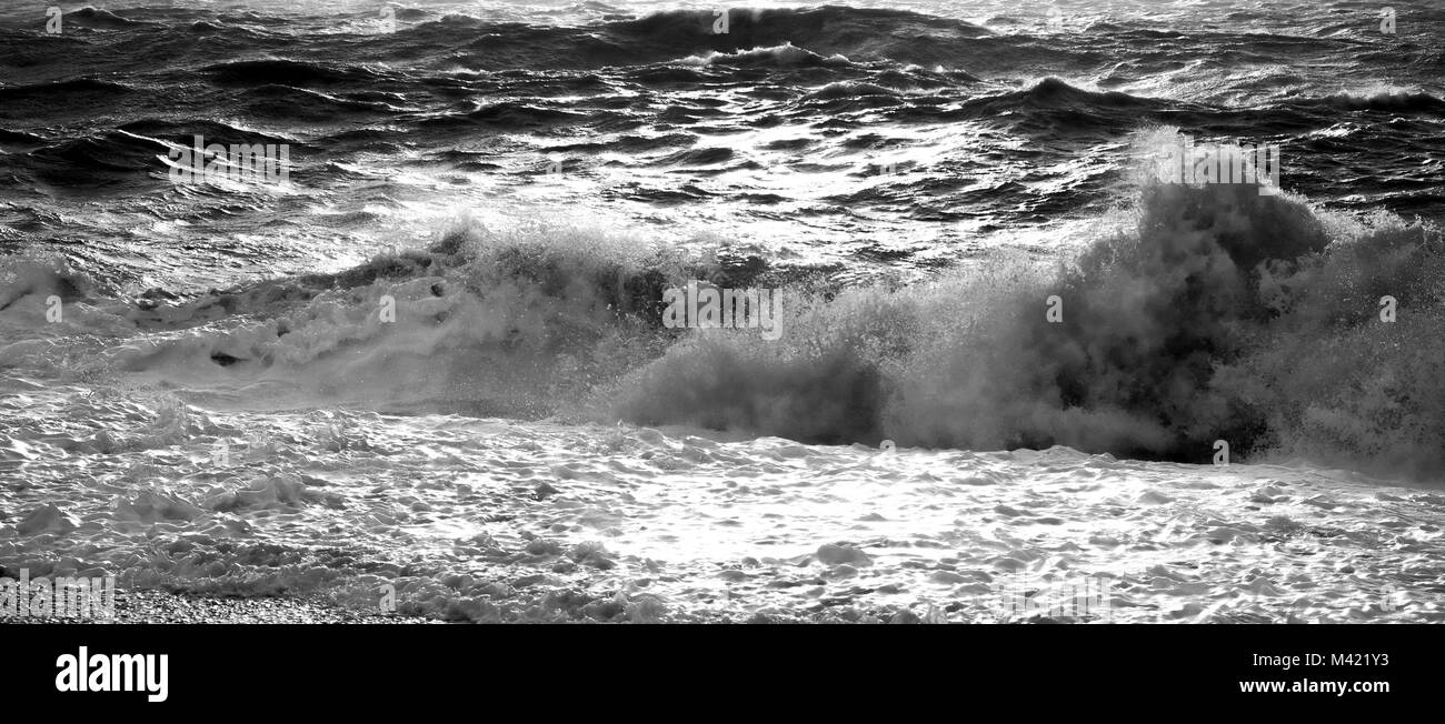 black and white photograph of a wave crashing and breaking the sea is rough behind, rough sea, water, wave, power, energy, natural energy, tide, tidal Stock Photo