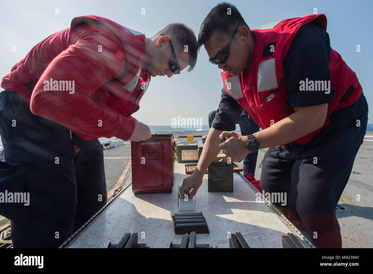 180208-N-NB544-144 SOUTH CHINA SEA (Feb. 8, 2018) Gunner's Mate Seaman Michael Norris, left, from Oakdale, Calif., and Gunner's Mate 2nd Class Tristan Jesusa, from Baras, Philippines, load 9 mm pistol magazines during a gun shoot aboard the amphibious assault ship USS Bonhomme Richard (LHD 6). Bonhomme Richard is operating in the Indo-Asia-Pacific region as part of a regularly scheduled patrol and provides a rapid-response capability in the event of a regional contingency or natural disaster. (U.S. Navy photo by Mass Communication Specialist 2nd Class Kyle Carlstrom/Released) Stock Photo