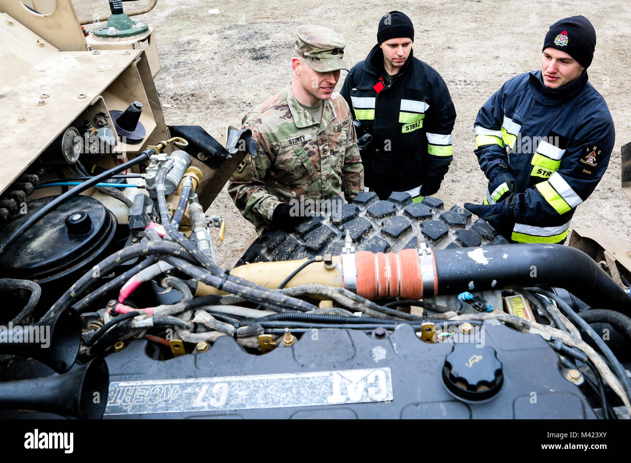 U.S. Army Staff Sgt. Clayton Storey (right), a Daytona, Ohio native, and field maintenance team chief with the 82nd Brigade Engineer Battalion, 2nd Armored Brigade Combat Team, 1st Infantry Division, shows a member of the Polish 5430rd Military Fire Brigade and an emergency first responder the engine of a Mine-Resistant Ambush Protected Vehicle in Zagan, Poland on Feb. 9, 2018.  Storey and his unit are part of a multinational training exercise designed to increase interoperability during Atlantic Resolve.  (U.S. Army photo by Spc. Hubert D. Delany III / 22nd Mobile Public Affairs Detachment) Stock Photo