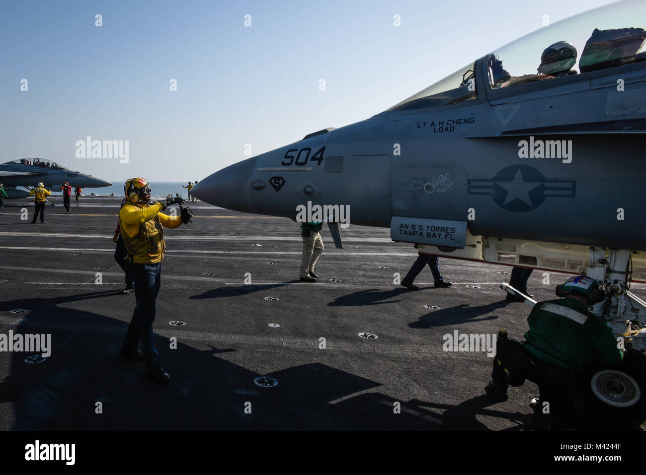 180115-N-VN584-1394 ARABIAN GULF (Jan. 15, 2018) Aviation Boatswain’s Mate (Handling) 1st Class Paul Hall signals to tie-down an EA-18G Growler, assigned to the Cougars of Electronic Attack Squadron (VAQ) 139, on the flight deck of the aircraft carrier USS Theodore Roosevelt (CVN 71). Theodore Roosevelt and its carrier strike group are deployed to the U.S. 5th Fleet area of operations in support of maritime security operations to reassure allies and partners and preserve the freedom of navigation and the free flow of commerce in the region. (U.S. Navy photo by Mass Communication Specialist 3rd Stock Photo