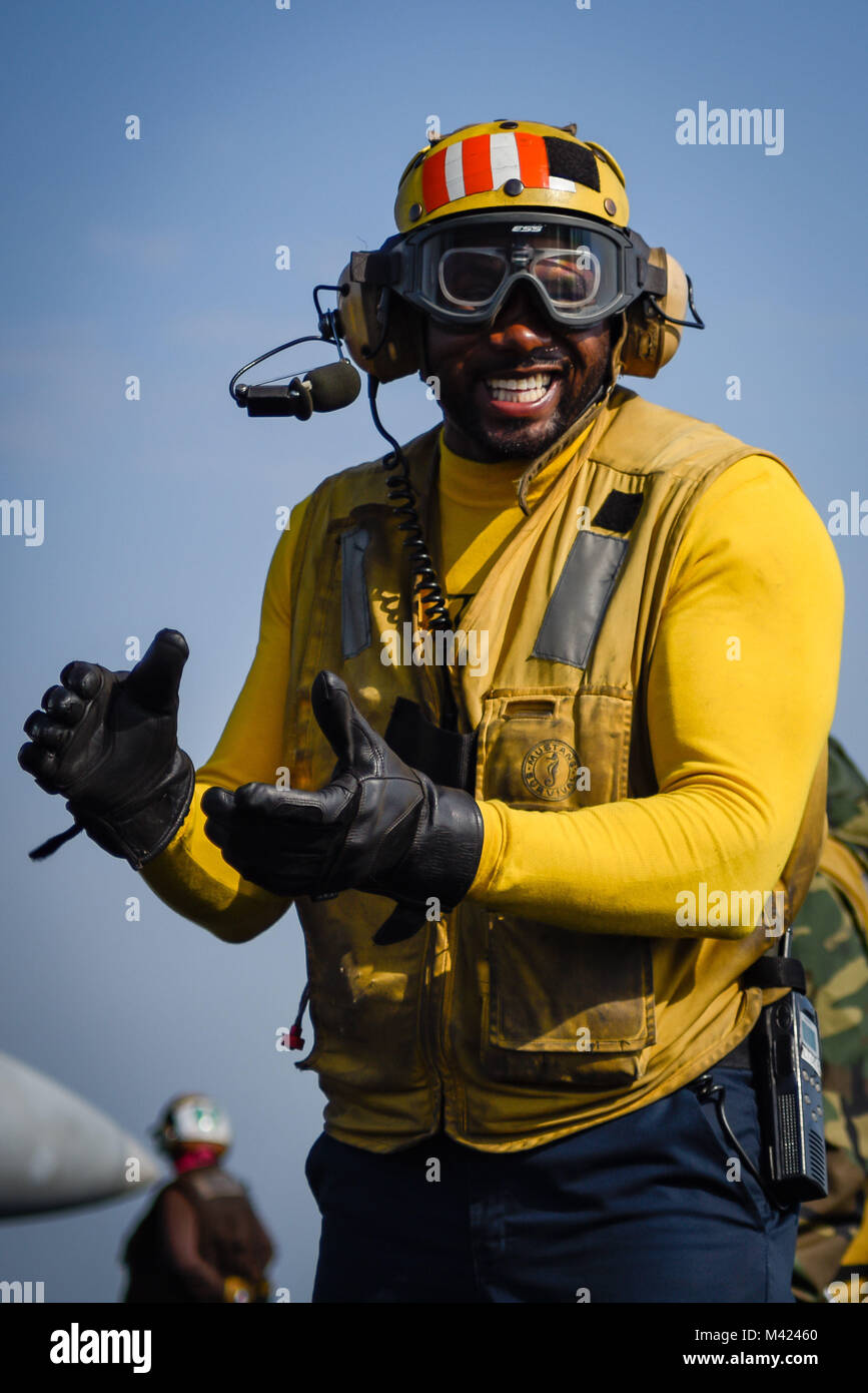 180115-N-VN584-1890 ARABIAN GULF (Jan. 15, 2018) Aviation Boatswain’s Mate (Handling) 1st Class Paul Hall smiles on the flight deck of the aircraft carrier USS Theodore Roosevelt (CVN 71). Theodore Roosevelt and its carrier strike group are deployed to the U.S. 5th Fleet area of operations in support of maritime security operations to reassure allies and partners and preserve the freedom of navigation and the free flow of commerce in the region. (U.S. Navy photo by Mass Communication Specialist 3rd Class Alex Corona/Released) Stock Photo