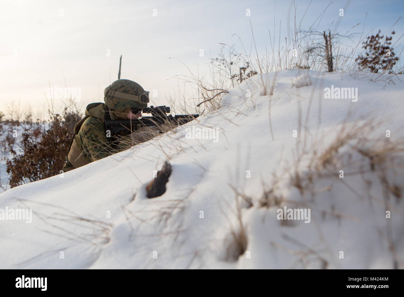 Reserve Marine Lance Cpl. Aaron Harrison, a medium tactical vehicle replacement driver with Company F, 4th Tank Battalion, 4th Marine Division, provides security to an Abrams M1A1 Main Battle Tank during a resupply mission at exercise Winter Break 2018, aboard Camp Grayling, Michigan, Feb. 10, 2018. Winter Break 18 allows the Marines of Fox Co. to develop essential mechanized infantry tactics and offensive and defensive capabilities in an austere cold weather environment. This exercise greatly increases the Reserve Component’s interoperability with the Active Component. Stock Photo