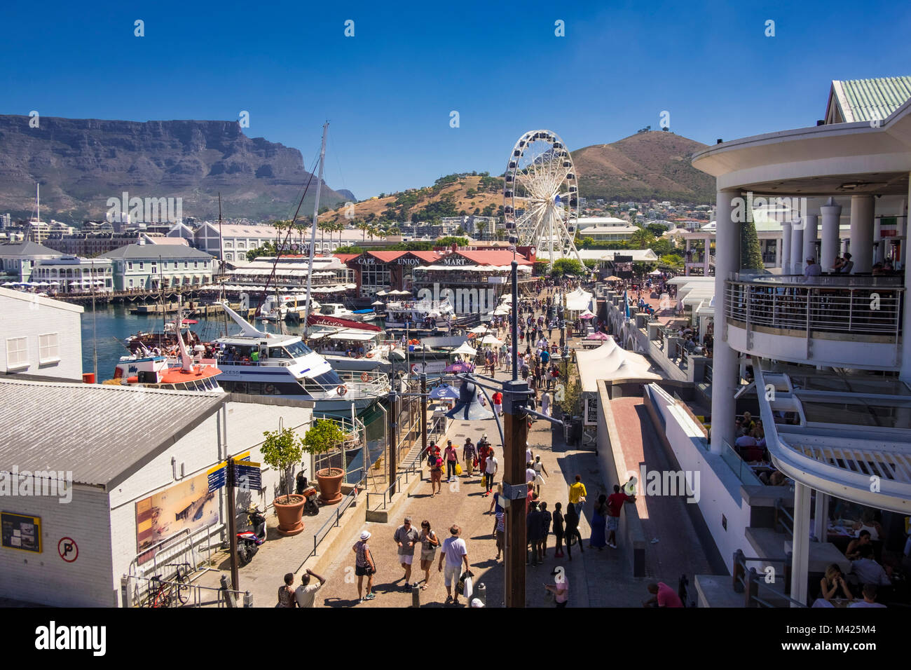 Cape Town, Tourists and shoppers at the V&A Waterfront, Cape Town, South Africa, showing Cape Union Mart, the Cape Wheel and Table Mountain Stock Photo