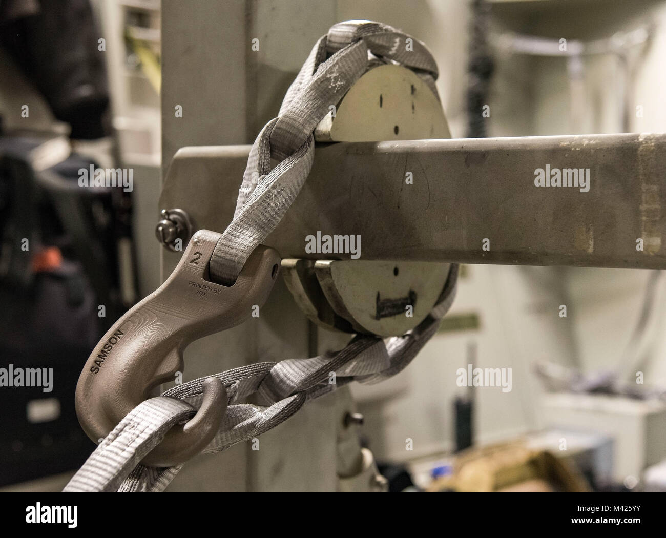 A synthetic tie-down chain rests in the slotted interface designed for steel chains used on a buffer stop assembly, Jan. 30, 2018 at Dover Air Force Base, Del. The buffer stop assembly is a device used during specific C-17 Globemaster III airdrop missions to keep pallets from shifting forward in the cargo compartment. (U.S. Air Force photo by Roland Balik) Stock Photo