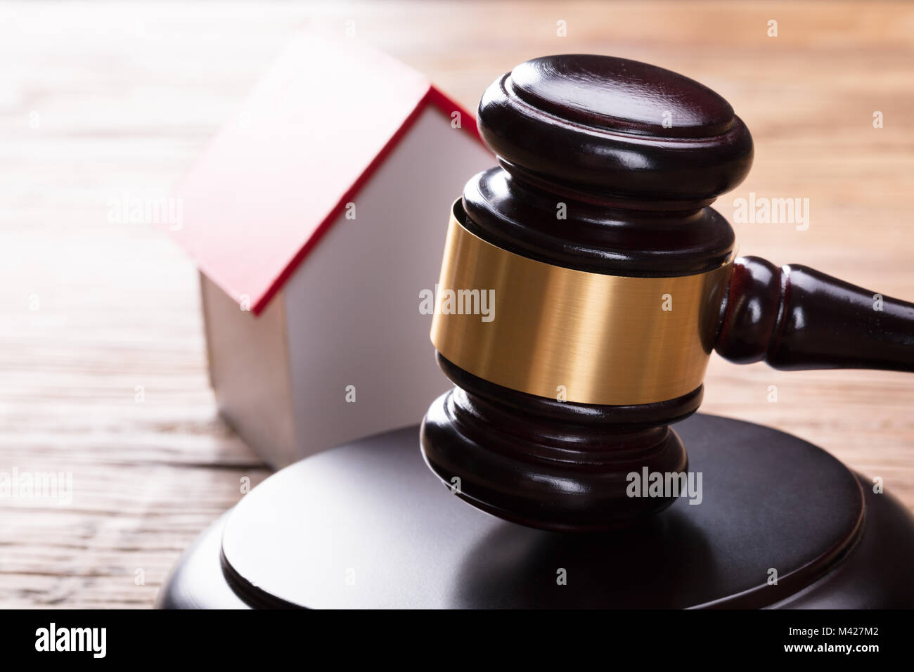 Close-up Of House Model With Gavel On Wooden Table Stock Photo