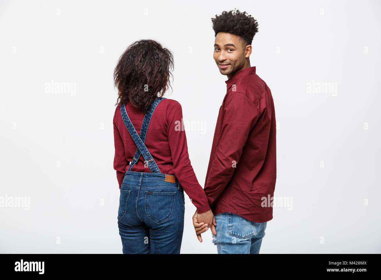 Portrait rear view of young afro american couple holding hands isolated ...
