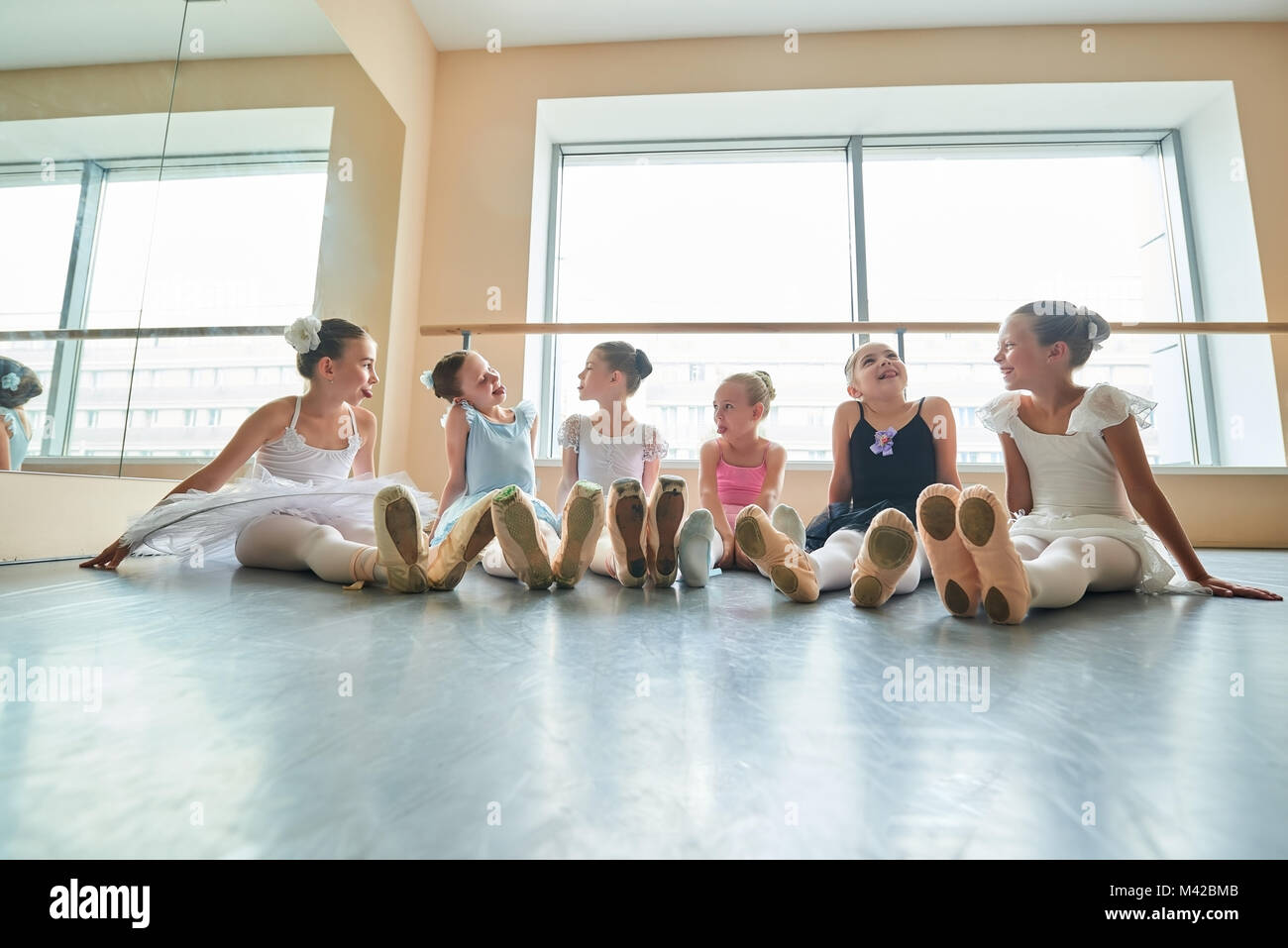 Cute ballerinas having fun in studio. Six young ballerinas showing tongues to each other and laughing. They are good friend. Stock Photo