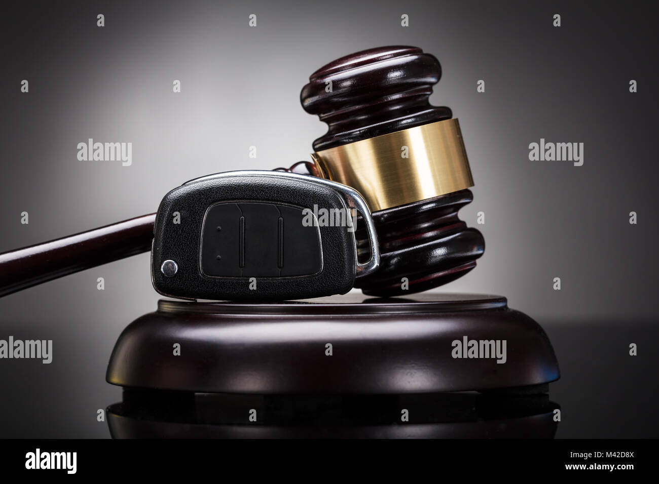 Close-up Of Gavel And Car Key On Sounding Block Against Grey Background Stock Photo