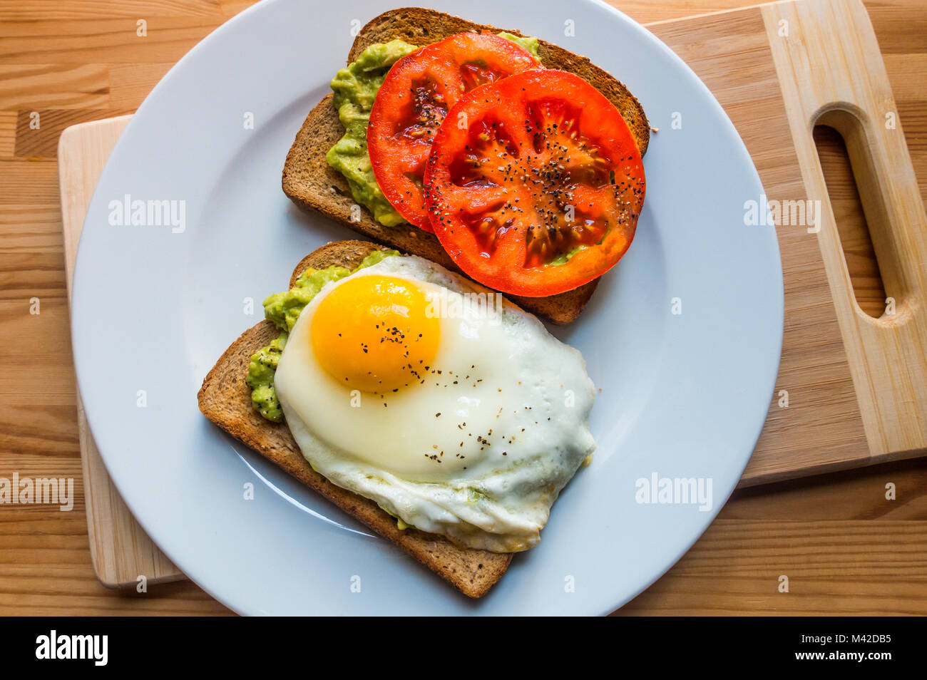 Avocado toast with sliced tomato and a fried egg Stock Photo Alamy