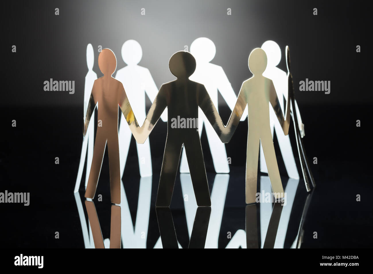 Close-up Of Paper Cut Out Human Figures On Grey Background Stock Photo