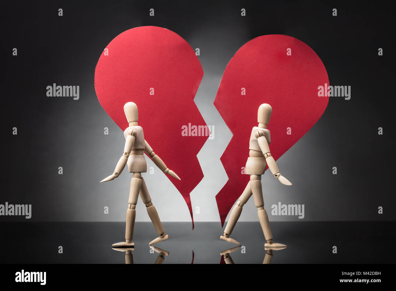 Two Wooden Dummy Standing Against Each Other With Broken Red Heart On Grey Background Stock Photo
