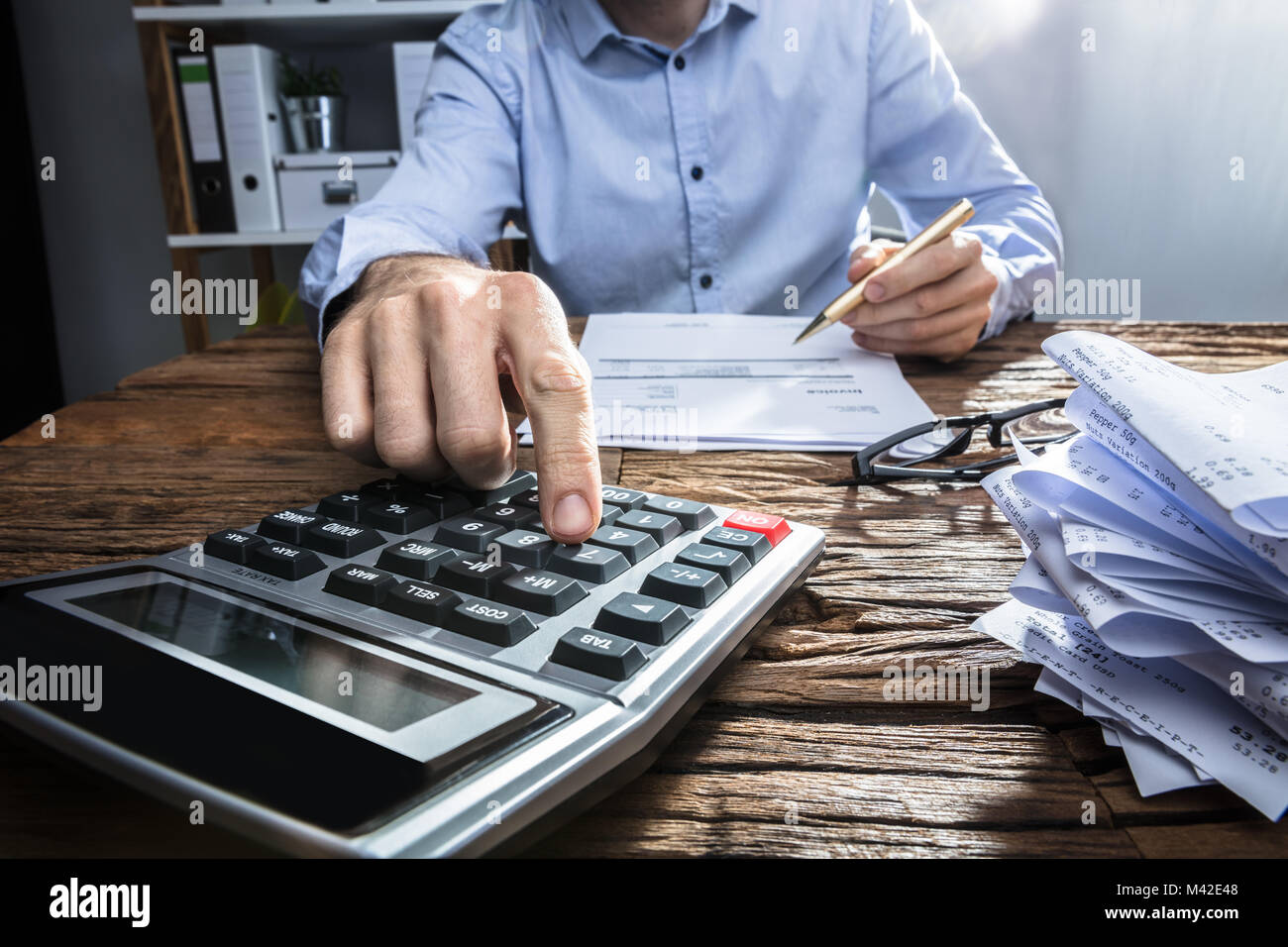 Close-up Of A Businessperson's Hand Calculating Invoice With Calculator At Workplace Stock Photo