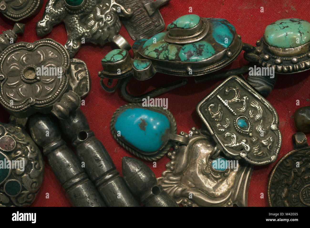 Antique Tibetan silver man's ornaments: men's earrings with turquoise, amulets, Buddhist knives. Stock Photo