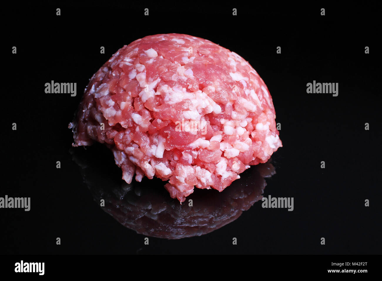Minced meat. Raw pork meat on black reflective studio background. Isolated black shiny mirror mirrored background for every concept.. Stock Photo